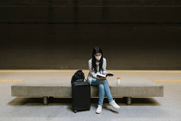 Weiblicher Fahrgast liest ein Buch, während er in der U-Bahn-Station sitzt - EGAF01000