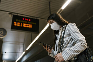 Female passenger using phone while waiting at railroad station - EGAF01002