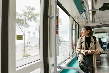 Frau mit Elektroroller schaut weg, während sie in der Straßenbahn telefoniert - VABF03984