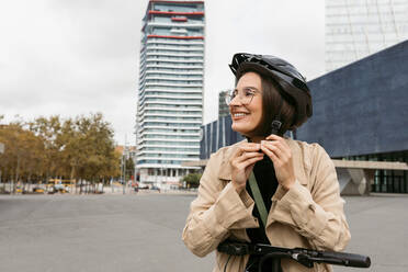 Lächelnde Frau mit Fahrradhelm auf der Straße in der Stadt - VABF03995