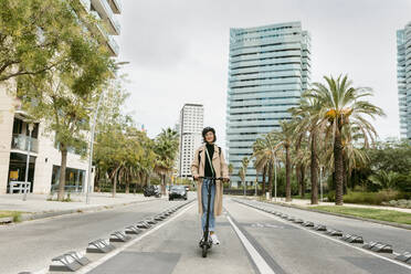 Frau fährt elektrischen Roller auf der Straße in der Stadt - VABF04007
