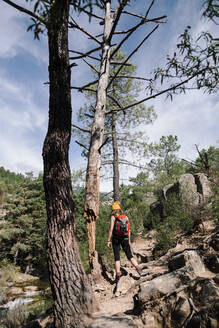 Wanderin mit Rucksack auf einem Felsenpfad im Wald bei La Pedriza, Madrid, Spanien - MRRF00655