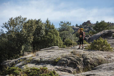 Wanderer bewundert die Aussicht, während er auf dem Felsenberg von La Pedriza, Madrid, Spanien steht - MRRF00661