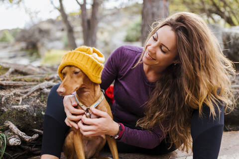 Smiling woman sitting with dog in forest at La Pedriza, Madrid, Spain stock photo