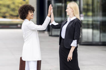 Geschäftsleute, die sich im Freien stehend mit einem High-Five begrüßen - GGGF00131