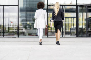 Businesswomen walking on footpath against building - GGGF00137