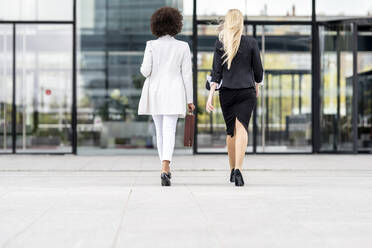 Geschäftsfrauen, die auf dem Fußweg gegen ein Gebäude laufen - GGGF00137