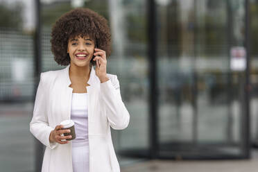 Young businesswoman talking on mobile phone while standing outdoors - GGGF00152