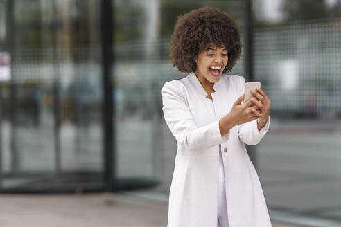 Young businesswoman using mobile phone while standing outdoors - GGGF00157