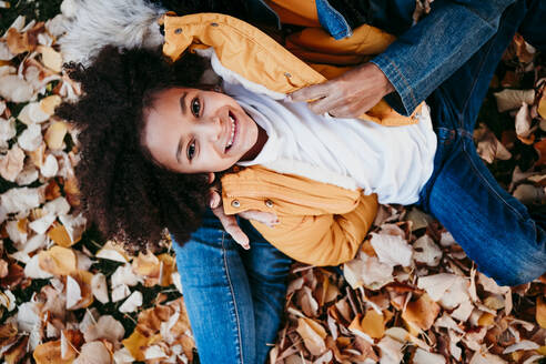 Girl smiling while lying on mother lap at park - EBBF01439