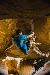 Man climbing boulder at Hampi, Karnataka, India - JMPF00559