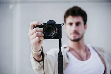 Mann fotografiert durch die Kamera, während er an der Wand steht - EBBF01522