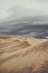 Unbekannter Tourist spaziert entlang der Dünen im Great Sand Dunes National Park während eines Urlaubs in Colorado - ADSF17372