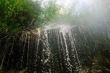 Amazing view of waterfall cascade and stream flowing through forest - ADSF17400