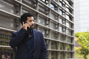 Businessman talking on smart phone in city - PNAF00054