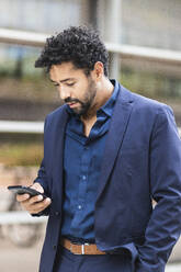 Unternehmer, der ein Mobiltelefon benutzt, während er in der Stadt steht - PNAF00099