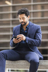 Male business person using mobile phone in city - PNAF00104