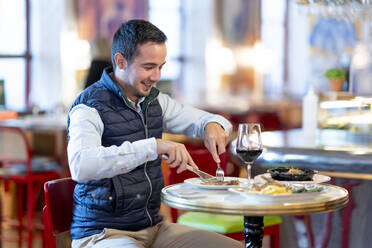 Junger Mann beim Mittagessen in einem Restaurant - CJMF00350