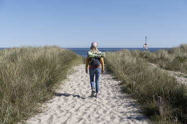 Rear view of woman with backpack walking on beach - CHPF00705