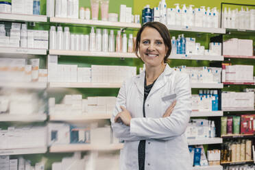 Confident pharmacist with arms crossed in chemist shop - MFF06801