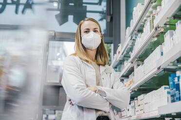 Saleswoman with arms crossed wearing protective face mask in chemist store - MFF06815