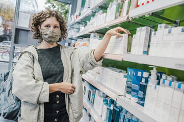 Female customer wearing protective face mask in chemist shop - MFF06851