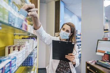 Apothekerin mit Schutzmaske bei der Arbeit in der Apotheke - MFF06859