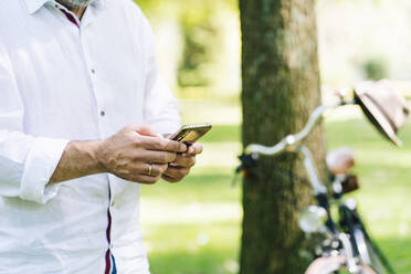 Älterer Mann benutzt Mobiltelefon in einem öffentlichen Park - DGOF01664