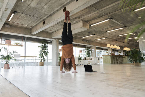 Mittlerer erwachsener Mann macht Handstand im Wohnzimmer zu Hause - FMKF06750