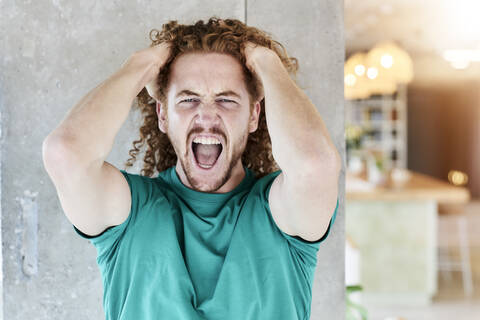 Man in aggression shouting while standing against column at home stock photo