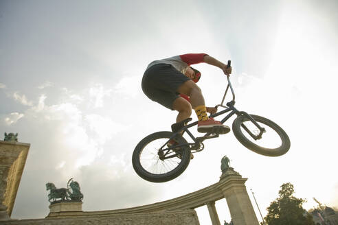 Junger Mann bei einem Stunt auf einem BMX-Rad auf dem Heldenplatz, Budapest, Ungarn - AJOF00547