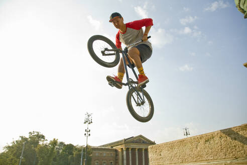 Junger asiatischer Mann macht Mid-Air-Stunt auf BMX-Rad gegen den Himmel, Heldenplatz, Budapest, Ungarn - AJOF00550