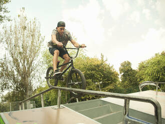 Junger kaukasischer BMX-Radfahrer beim Üben im Skateboard-Park - AJOF00552