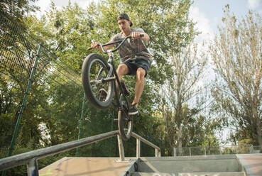 Young male BMX biker practicing at skateboard park - AJOF00553