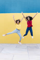 Fröhliches lesbisches Paar springt gegen gelbe Wand - RDGF00215