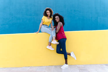 Happy lesbian couple spending time together against blue wall - RDGF00228