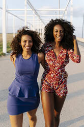 Happy female friends walking on sunny day - RDGF00233