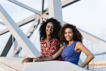 Lächelnde Freundinnen stehen auf einer Brücke - RDGF00250