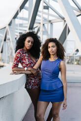 Confident young female friends standing on bridge - RDGF00252