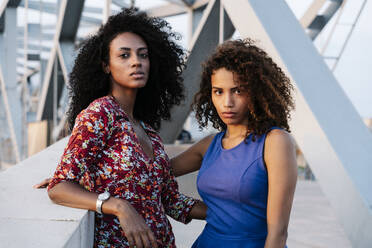 Confident female friends standing by retaining wall on bridge - RDGF00253