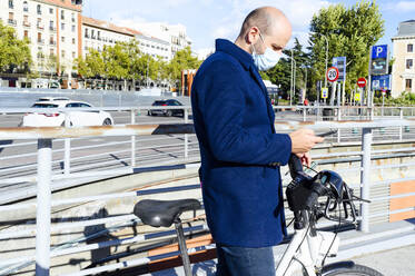 Mann benutzt sein Smartphone, während er auf der Straße steht, während COVID-19 - PGF00208