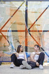 Junges Paar ruht sich im Sitzen am Tor aus - IFRF00062