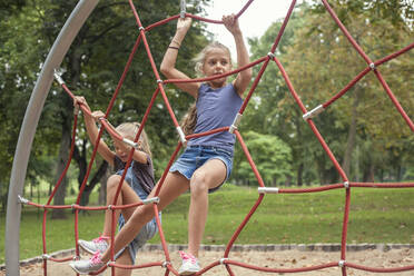 Girls climbing on jungle gym at playground - AJOF00570