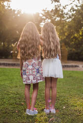 Mädchen stehen im Park bei Sonnenuntergang - AJOF00599