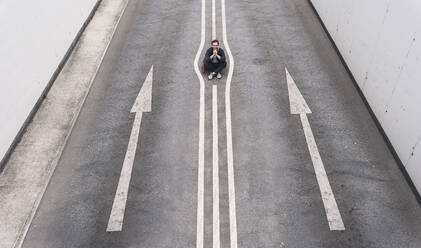 Young man sitting on road marking - UUF22069