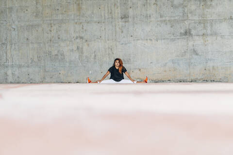 Athlete stretching while exercising against wall stock photo