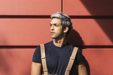 Young man looking away against red wall - PNAF00151