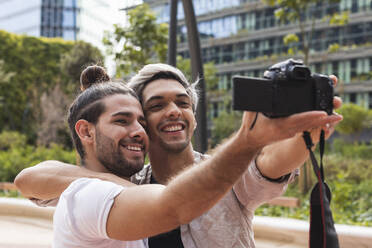 Lächelndes schwules Paar beim Fotografieren durch die Kamera in der Stadt - PNAF00164