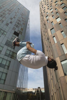 Young man practicing somersault against building in city - PNAF00165