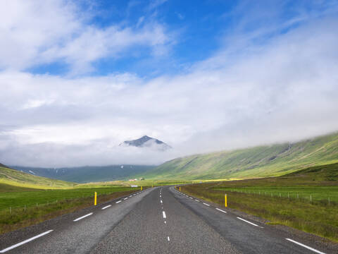 Tiefhängende Wolken über einer leeren isländischen Landstraße, lizenzfreies Stockfoto